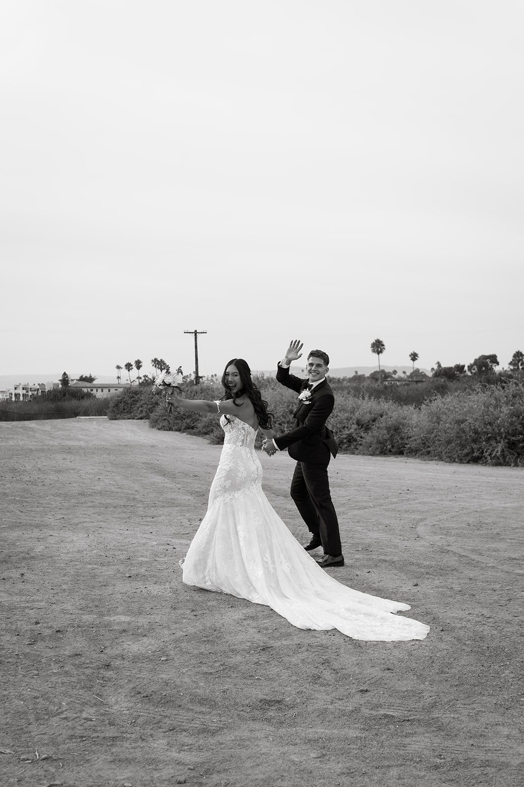 Bride and groom waving and walking together, black and white